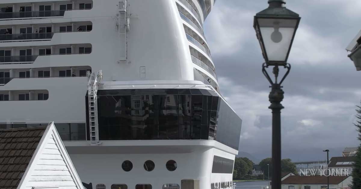 a huge cruise ship passing by a tiny town in norway