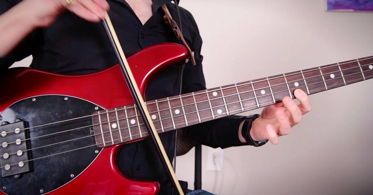 a guy playing a bass guitar with a violin bow