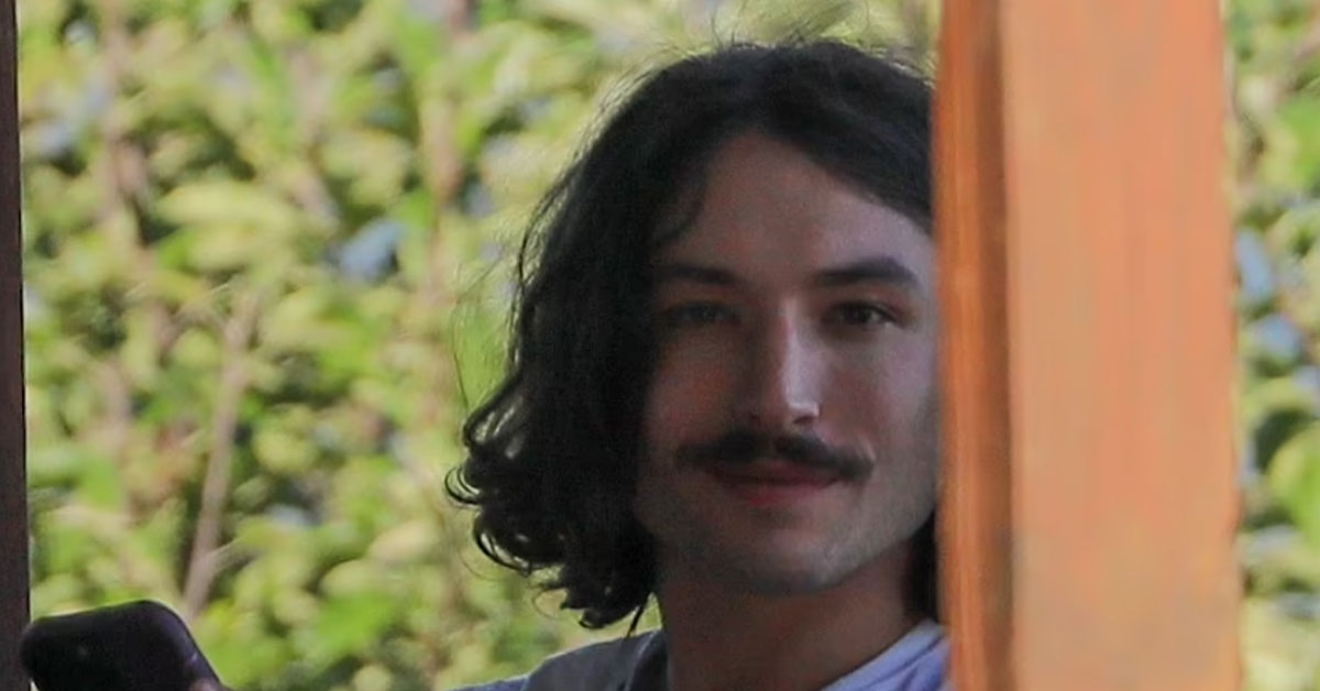 Ezra Miller gives a smirk while on the deck of their house