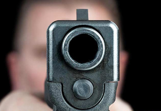 man holding a gun pointing at the camera