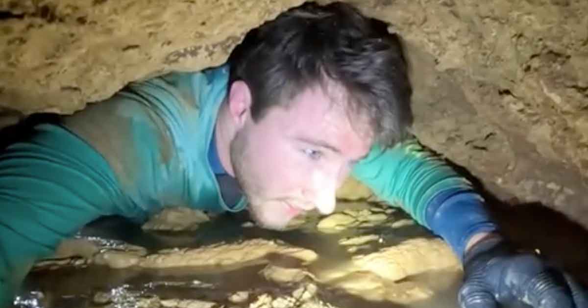 man crawling through a cave