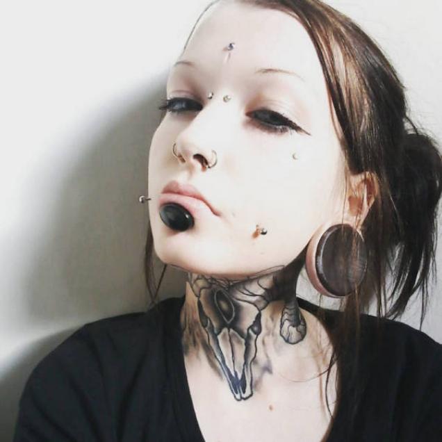 pale woman with extreme facial piercings.